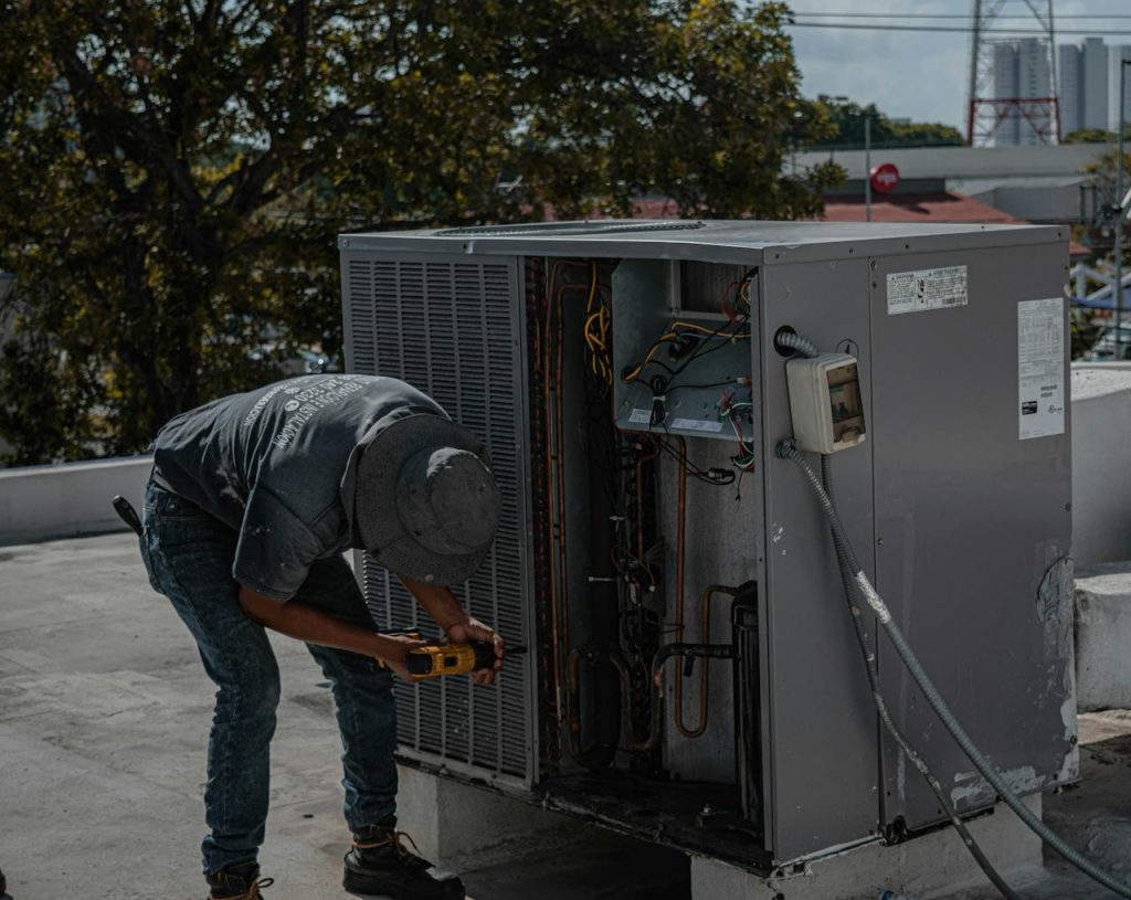 A technician from BDS Services Ltd is repairing an air conditioning unit on a rooftop, demonstrating skilled manual work.